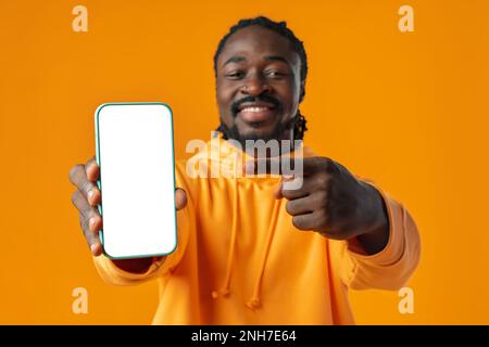 Smiling african man pointing at cellphone with blank screen with copy space Stock Photo