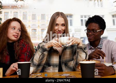 Smiling african american guy showing funny video or party photos on smartphone for diverse best friends, group of happy mixed race students meeting in Stock Photo
