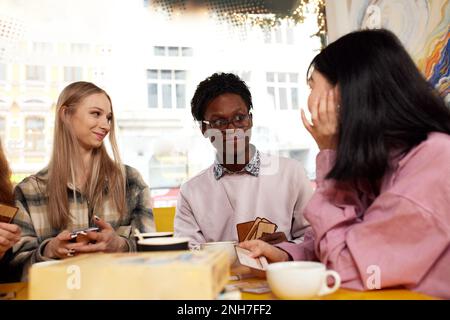 Smiling african american guy showing funny video or party photos on smartphone for diverse best friends, group of happy mixed race students meeting in Stock Photo
