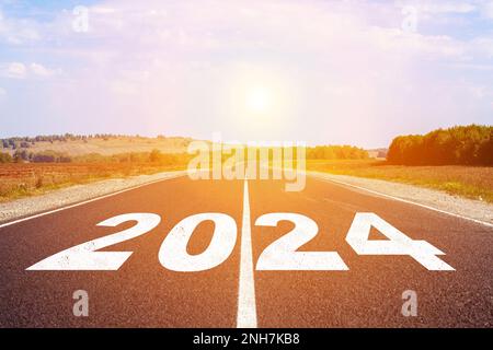 2024 written on highway road in the middle of empty asphalt road and beautiful blue sky. Concept for vision new year 2024. Stock Photo