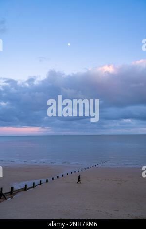 Walker on the beach at Walton on the Naze Essex Stock Photo