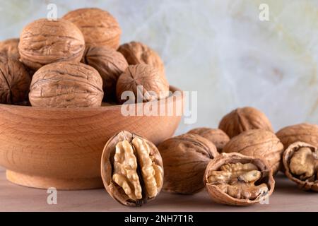 Walnut kernels and cracked walnuts on wooden background, front view Stock Photo