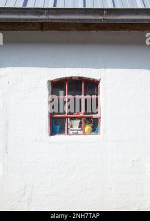 Cosy little white house with a small red window that permits to see objects and a danish sign Stock Photo
