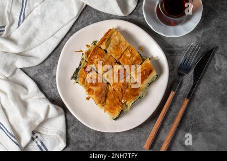 Spinach pastry. Traditional Turkish cuisine delicacies. Spinach pie made with breakfast phyllo on a dark background. Top view Stock Photo