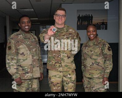 U.S. Air Force Staff Sgt. Joshua Brown (center), 86th Aeromedical Evacuation Squadron medical material noncommissioned officer in charge, stands with Brig. Gen. Otis C. Jones, 86th Airlift Wing commander (left), and 86th Airlift Wing Command Chief Master Sgt. Charmaine Kelley, (right), at Ramstein Air Base, Germany, July 21, 2022. Brown received Jones’ first coin since taking command . Stock Photo