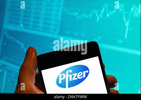In this photo illustration, the American multinational pharmaceutical corporation Pfizer logo is seen displayed on a smartphone with an economic stock exchange index graph in the background. (Photo by Budrul Chukrut / SOPA Images/Sipa USA) Stock Photo