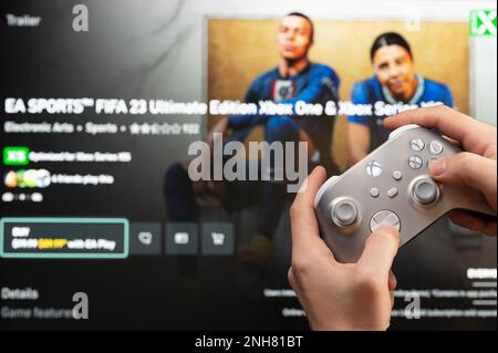 New york, USA - February 20, 2023: Gamer start new FIFA 23  Game on xbox console with joystick in hand Stock Photo