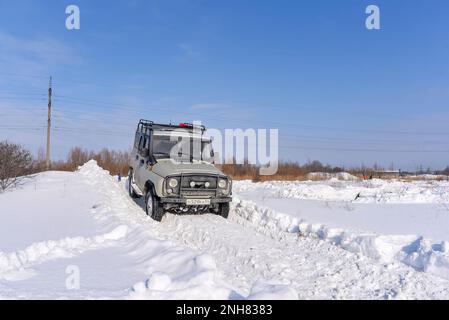 Russian offroad SUV 'UAZ hunter 469' 4x4 rides on a snowy mountain in winter in a field on a bad road. Stock Photo