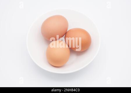 Three chicken eggs in a white bowl Stock Photo
