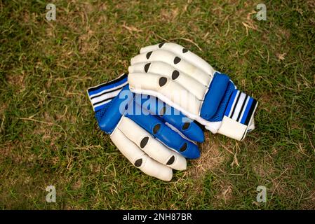 cricket gloves laying on grass playing field Stock Photo