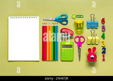 Frame from school and office supplies Paper clips, pens, calculator, sharpener, notepad, stapler isolated on green background Flat lay Top view Back t Stock Photo