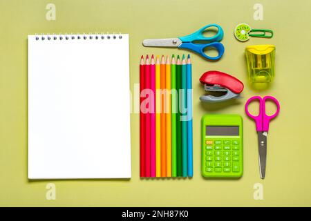 Frame from school and office supplies Paper clips, pens, calculator, sharpener, notepad, stapler isolated on green background Flat lay Top view Back t Stock Photo