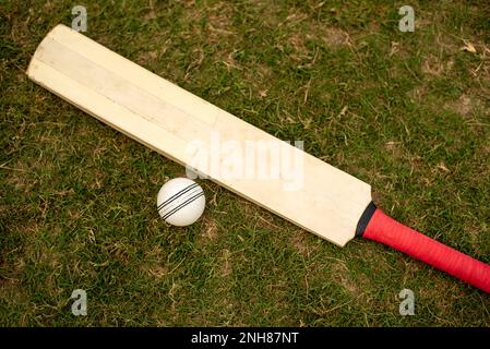 Cricket bat and ball on playing grass field pitch Stock Photo