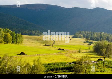 Sloping field under the hill, under a cloudy sky. Stock Photo