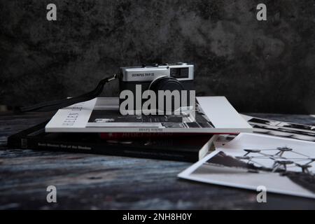 Olympus trip vintage camera in still life image on stack of photo books and black and white prints, Stock Photo
