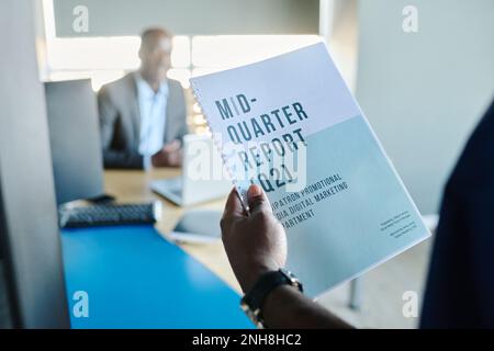 Close-up of young male economist holding mid-quarter report while standing by door of his boss office and going to enter Stock Photo