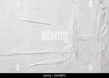 Blank white crumpled and creased paper. White sheet of crumpled paper glued to the wall. Beautiful abstract artistic white empty street poster paper t Stock Photo
