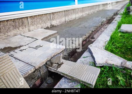 Replacement and repair of the blind area of the building. Laying stone tiles around the house. Construction theme.. Stock Photo