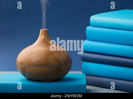 wood fragrance on the desk table with natural oils essence vapor, with blue and teal colored books Stock Photo