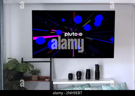 Hi, USA - May 21, 2020: Pluto TV cable service provider logo with graphic background on a home entertainment wall mounted flat screen. Stock Photo