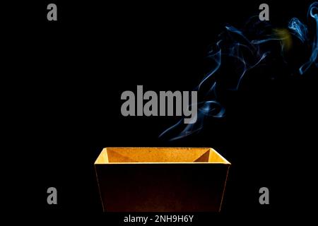 Smoke coming out of a wooden box. Isolated against a black background. Stock Photo