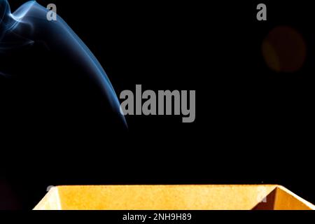 Smoke coming out of a wooden box. Isolated against a black background. Stock Photo