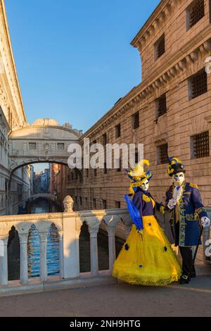 Carnival goers dressed in splendid costumes and masks during Venice Carnival 2023 at St Marks Square by Bridge of Sighs, Venice, Italy in February Stock Photo