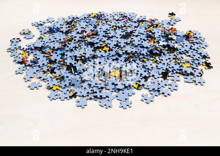 pile of blue puzzle pieces on light brown wooden table Stock Photo