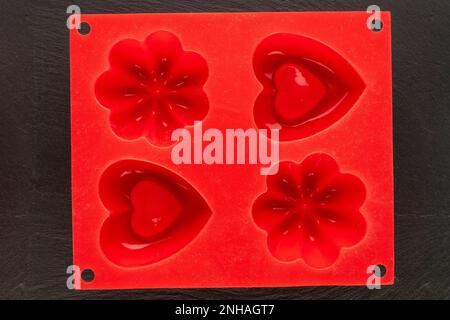 Red silicone cookie cutter on slate stone, macro, top view Stock Photo