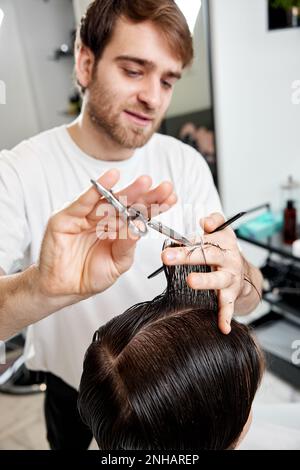Barber talking to caucasian man while sitting in chair Stock Photo