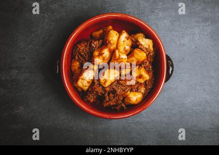 Potato gnocchi, Italian potato dumplings with stew on dark background. Copy space. Stock Photo