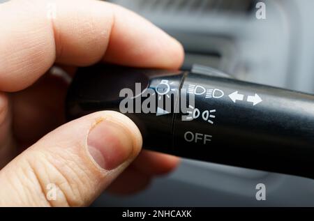 A person turns on the side lights of a car with a light switch. Close-up. Stock Photo