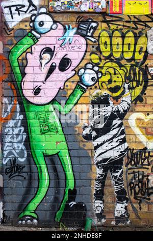 Street art graffitis on yellow brick wall in Camden Town district of London, England Stock Photo