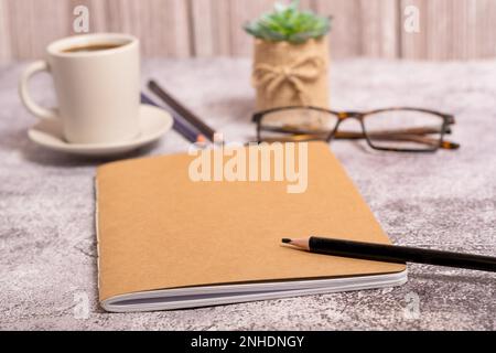 Closed notebook with brown covers, pencil, glasses and coffee cup with copy space Stock Photo