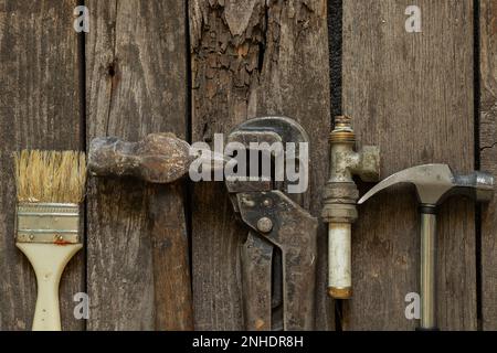 gas wrench hammer old rusty pipe and paintbrush lie on a wooden table in the kitchen, repair, tool set Stock Photo