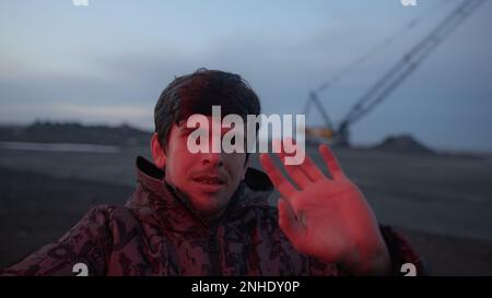 Young Serious Man Waving Red Light by Side of Road and Looking at Camera, Working Concept Stock Photo
