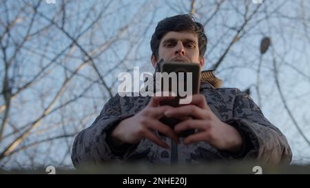 Young Man Using his Smartphone for Messaging and Applications, Bottom view Stock Photo