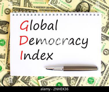 GDI global democracy index symbol. Concept words GDI global democracy index on white note on beautiful background from dollar bills. Pen. Business and Stock Photo