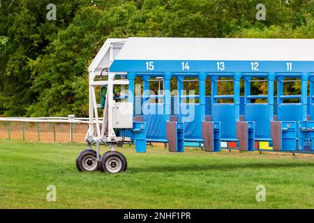 Blue horse racing starting gate on start by tractor machine at equiestrian racehorse hippodrome. Outdoor sport racecourse competition equipment Stock Photo