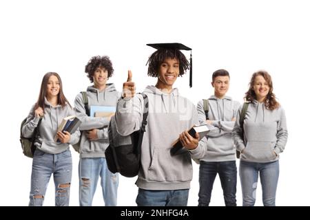 African american male student with a graduation hat gesturing thumbs up and other students posing in the back isolated on white background Stock Photo