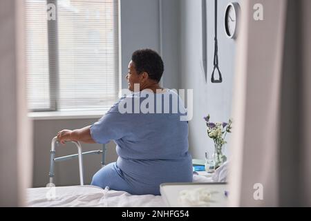 Back view of lonely senior woman in hospital room, minimal Stock Photo