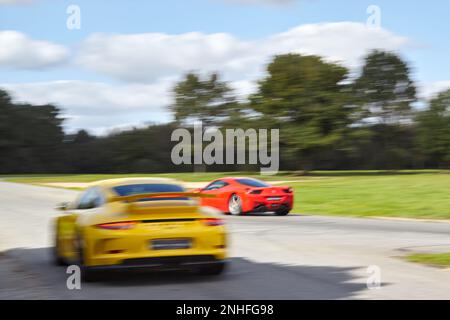 A red Ferrari and a yellow one running on a racing circuit with motion blur Stock Photo