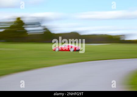 A red Ferrari running on a racing circuit with motion blur Stock Photo