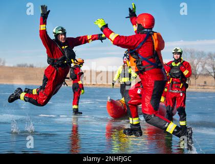 Waverly Fire's Tell Hanes, left, and Southeast Fire's Trey Wayne, right, jump over freezing water to high five while participating in a Surface Ice rescue technician course on Friday, Jan. 6, 2023, at Holmes Lake Park in Lincoln, Neb. The International Rescue and Relief department at Union college held rescue training course at Holmes Lake for students and local fire departments. (Kenneth Ferriera/Lincoln Journal Star via AP)