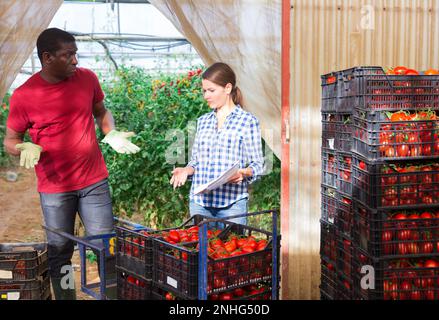 Irritated woman greenhouse owner talking to worker in warehouse Stock Photo