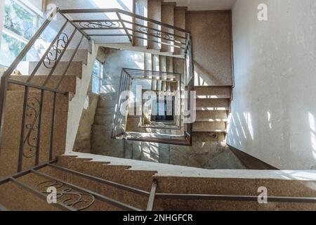 Square staircase, top view of the stairwell of a multistory building. Stairs looking down viewed from up. Stock Photo