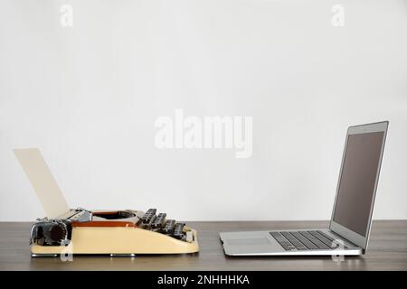 Old typewriter and laptop on table against light background, space for text. Concept of technology progress Stock Photo