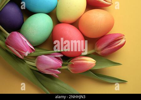 Fresh colorful tulip flowers and easter eggs on yellow background. Top view with. Happy easter greeting card. Stock Photo