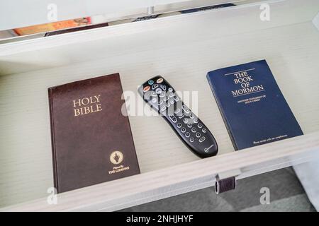 holy bible, book of mormon and tv remote inside the drawer of a hotel room Stock Photo
