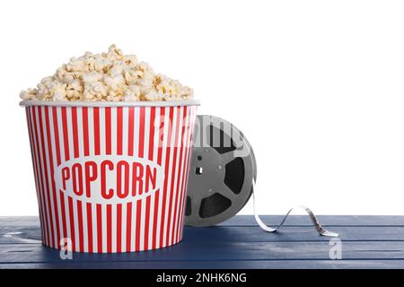 Delicious popcorn and movie reel on blue wooden table against white background Stock Photo